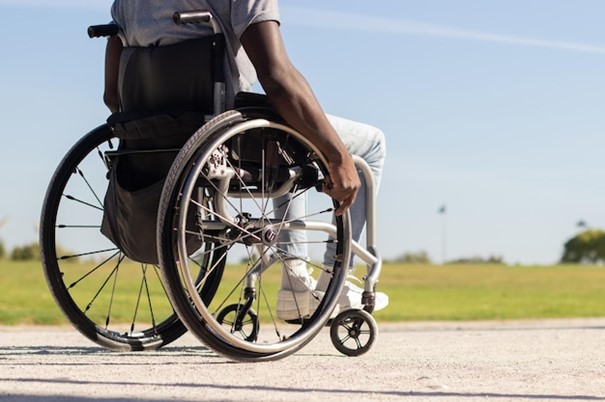 Free photo black man in wheelchair riding along park road